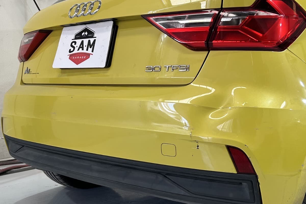 Auto Audi con defensa trasera golpeada y pintura igualada por código original antes del servicio